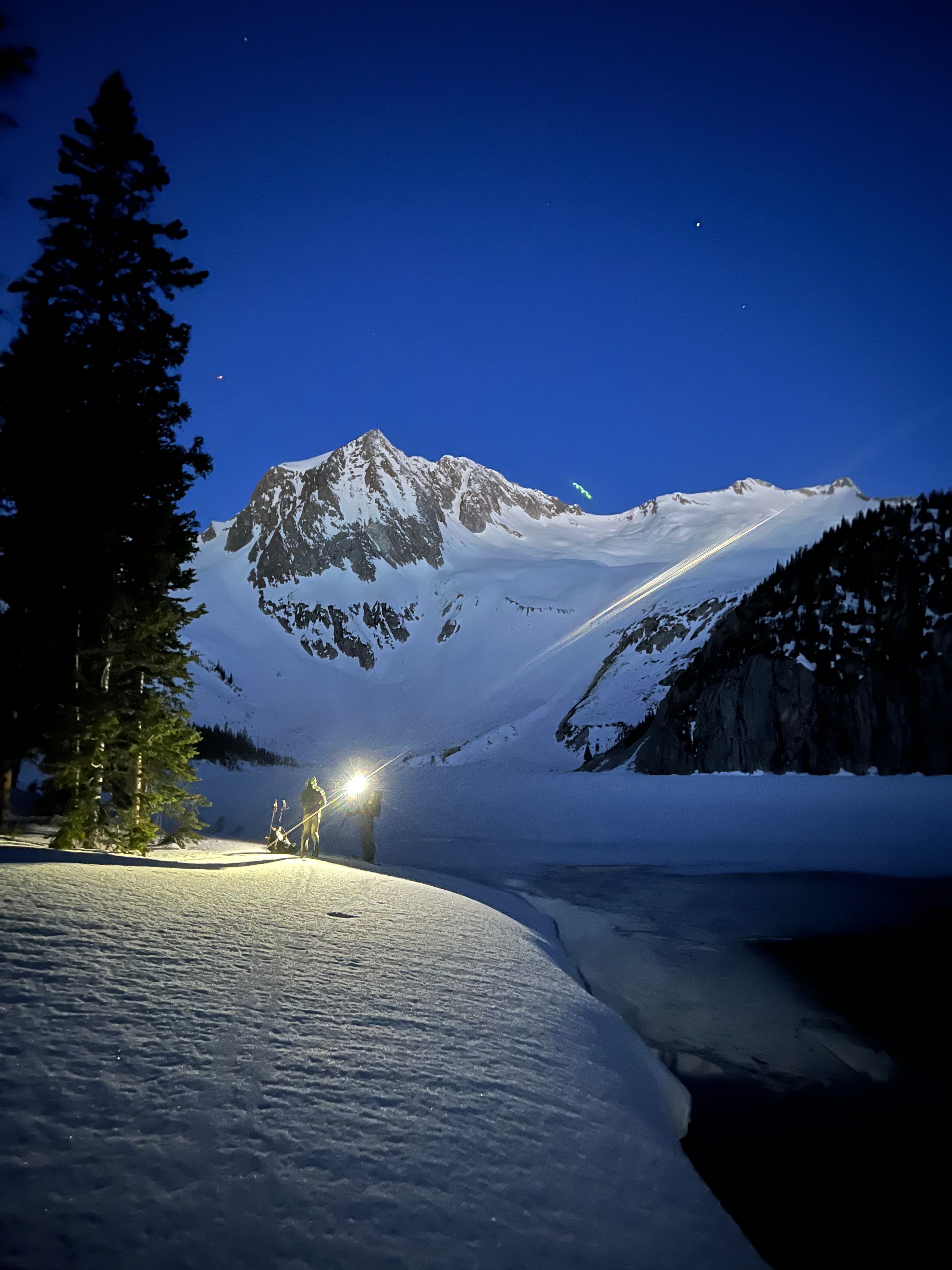 Backcountry skiers ascending a snowy peak at dawn